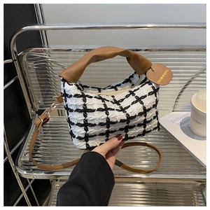 Détail du sac à main en tweed à carreaux avec poignée en cuir et étiquette décorative