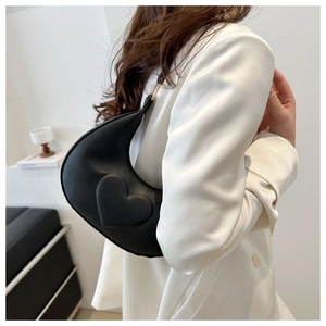 Détail du sac hobo croissant noir avec gaufrage en cœur porté à l'épaule