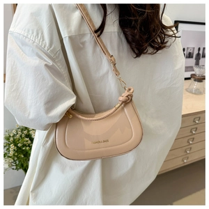 Détail du sac croissant crème montrant la texture du cuir lisse et la bandoulière réglable