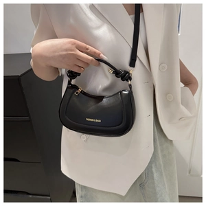 Détail d'un sac bandoulière noir en demi-lune avec poignée nouée et lettrage doré