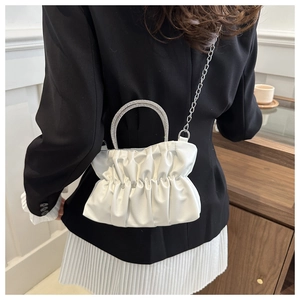Detailed shot of white pleated cloud bag featuring silver rhinestone-encrusted handle