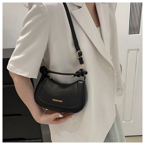 Détail du sac demi-lune noir avec lettrage doré et poignée à motif de nœud élégant