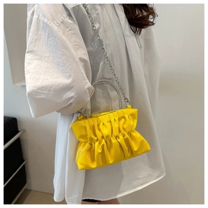 Detail of yellow ruched handbag with rhinestone-encrusted metal handle and silver chain