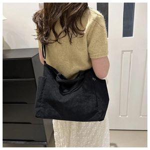 Détail de la texture velours côtelé noir et de la poche latérale de ce grand sac cabas