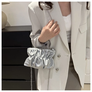 Detail of silver pleated cloud bag featuring rhinestone handle and sleek metal chain strap