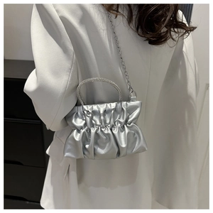 Close-up of silver pleated bag with rhinestone handle and metallic chain strap detail