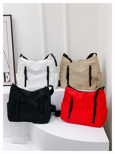 Detail of colorful nylon shoulder bags with side pockets and braided zipper pulls