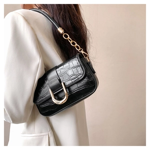 Détail du cuir embossé crocodile avec boucle dorée en U sur ce sac à bandoulière noir chic