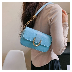 Détail du sac sous le bras bleu clair à motif crocodile et boucle dorée en U