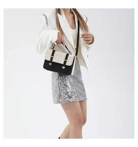 Detail of a chic straw-woven flap and black leather bag with gold metal buckle