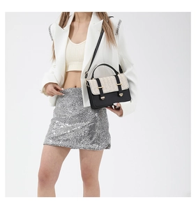 Detail of contrast color crossbody bag with woven flap and gold hardware on model