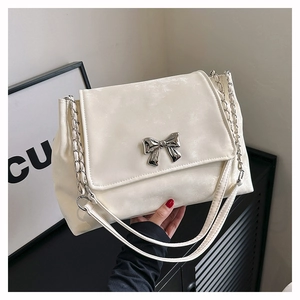 Detail of cream white shoulder bag with silver bow buckle and mixed chain strap