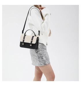 Detail of the woven straw flap and black leather handle on this stylish crossbody bag