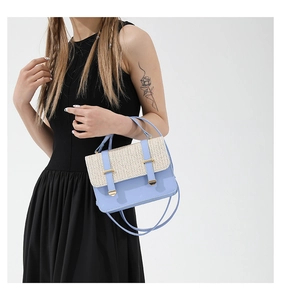 Model wearing a light blue woven straw handbag with a beige texture flap and gold buckle