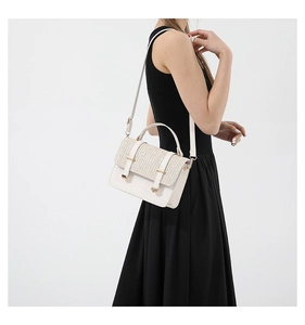 Detail of woven straw flap and light gold buckle on minimalist ivory crossbody bag