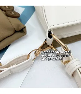 Dettaglio dei ganci in metallo dorato e tracolla in pelle bianca rimovibile della borsa