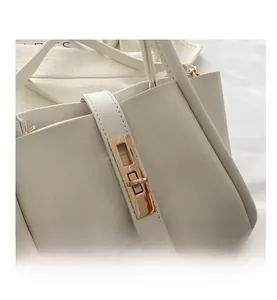 Detail of the golden rectangular metal twist lock on a minimalist cream leather tote bag