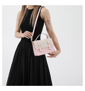 Detail of pink and beige woven crossbody bag with dual straps worn by a model