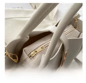Detail view of smooth golden zipper and premium leather texture on a cream tote bag