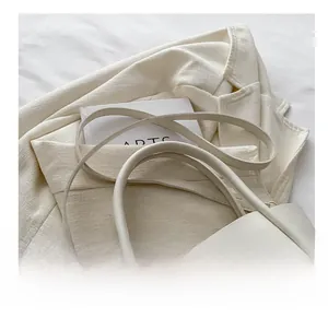 Detail of white leather tote bag featuring gold twist lock and adjustable shoulder strap