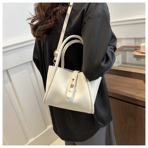 Detail of white leather tote bag featuring gold hardware and adjustable shoulder strap