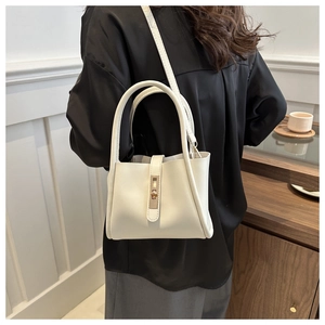 Detailed view of cream leather tote bag with metal lock worn on model shoulder