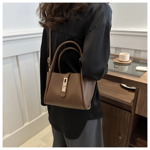 Detail view of coffee brown tote bag with gold metal clasp and adjustable shoulder strap