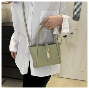 Close-up of light green tote bag with golden twist lock and cylindrical handles