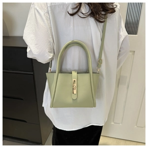 Detail of light green leather handbag showing metal turn-lock and adjustable shoulder strap