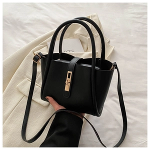 Detail of black matte leather tote bag with gold swivel lock and elegant top handle