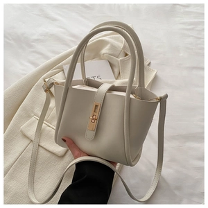 Detailed view of cream white trapezoid tote bag with gold twist lock and PU leather texture