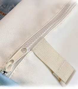 Detailed close-up of the smooth, high-quality nylon zipper on the white canvas bag