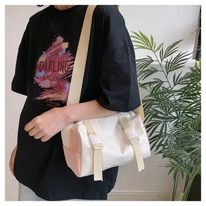 Detail of cream crossbody bag with adjustable strap and decorative white buckles
