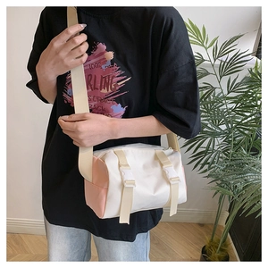 Detail of a cylinder crossbody bag with white and pink contrast and buckle straps