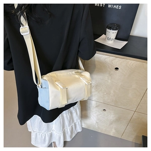Rear view of a model wearing the cream nylon cylinder crossbody bag with blue side pocket