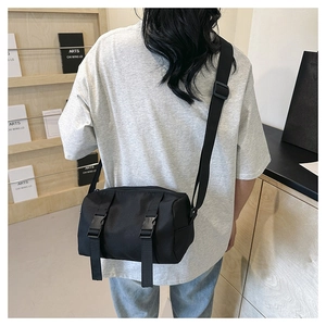 Detail of black utility crossbody bag featuring dual buckle straps and adjustable nylon strap