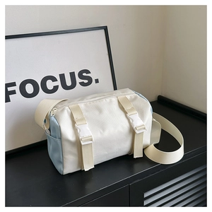 Detail of a minimalist two-tone cylinder crossbody bag with white buckles and wide strap