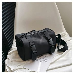 Detail of black nylon crossbody bag featuring double vertical straps and plastic buckles