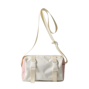 Fashionable cylinder crossbody bag in cream and pink colors with sporty buckle details