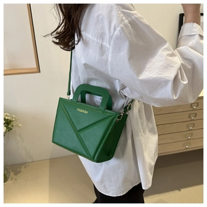 Close-up of green geometric folded handbag with FASHION text and matching strap