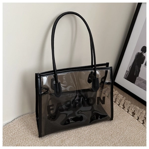Detail of transparent PVC tote bag with black leather edges and FASHION logo design