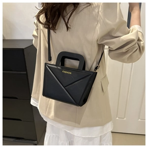 Detail van de zwarte geometrische crossbodytas met FASHION-tekst op een model