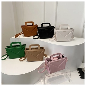 Detailed view of six colors of geometric origami PU leather handbags on a white podium