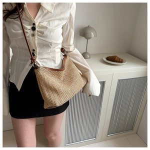 Detail of hand-woven straw crossbody bag with brown leather trim and fine stitching