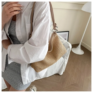 Detail showing the intricate woven texture and leather strap of this beige dumpling bag