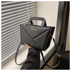 Detail of black geometric PU leather handbag featuring yellow Fashion text and U-shaped handle