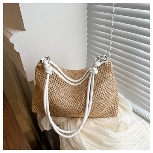 Detail of woven straw tote bag with white leather straps and silver metal hardware