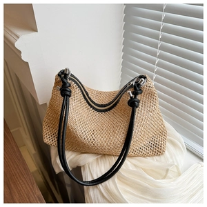 Close-up of woven straw bag with black knotted leather strap and silver metal ring