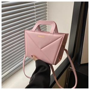 Detailed view of a pink geometric structured handbag with gold FASHION lettering text