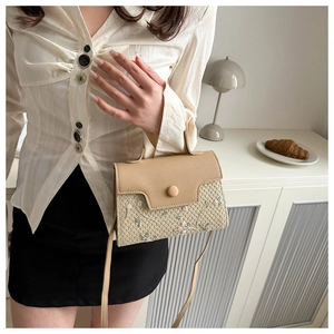 Detail of woven square crossbody bag with floral embroidery and beige leather flap